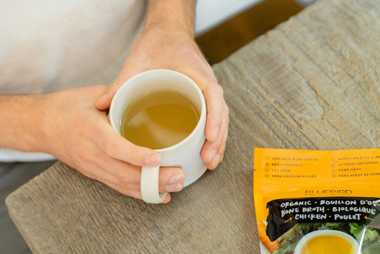 A woman interested in fitness and health breaks a fast by holding a cup of bone broth to support joints benefit hydration and promote drinking nutrients for overall wellness