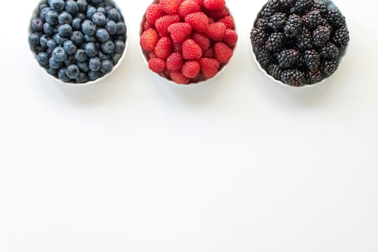 One cup of blueberries one cup of raspberries and a third cup of blackberries to symbolize a healthy diet with white space that represents fasting and the benefits of periods of no eating.